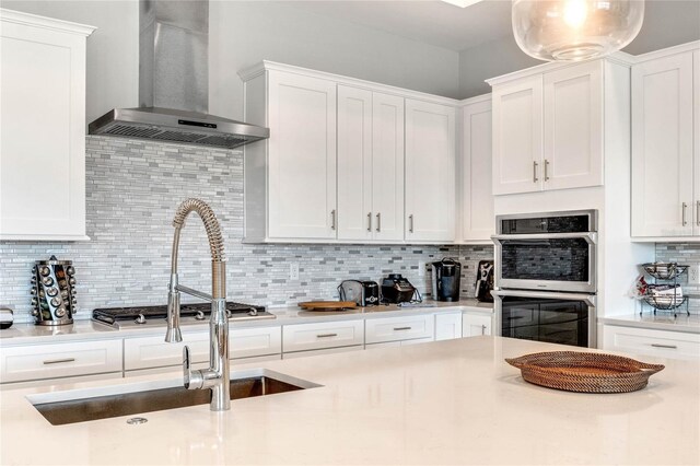 15947 Vetta Dr, Bella Collina, FL 34756 - kitchen featuring wall chimney range hood, double oven, decorative backsplash, white cabinetry, and light countertops