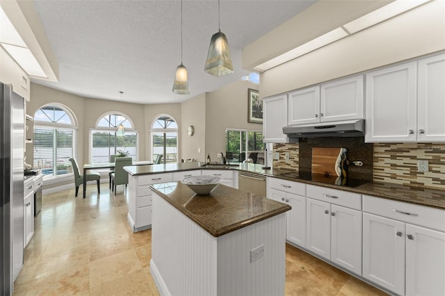 4536 N Landmark Dr, Orlando, FL 32817 - kitchen with under cabinet range hood, a peninsula, stainless steel appliances, decorative backsplash, and a center island