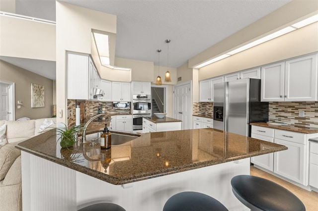 4536 N Landmark Dr, Orlando, FL 32817 - kitchen with appliances with stainless steel finishes, decorative backsplash, a peninsula, and dark stone countertops