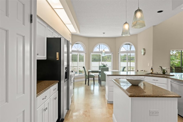 4536 N Landmark Dr, Orlando, FL 32817 - kitchen featuring appliances with stainless steel finishes, a kitchen island, white cabinets, hanging light fixtures, and a textured ceiling