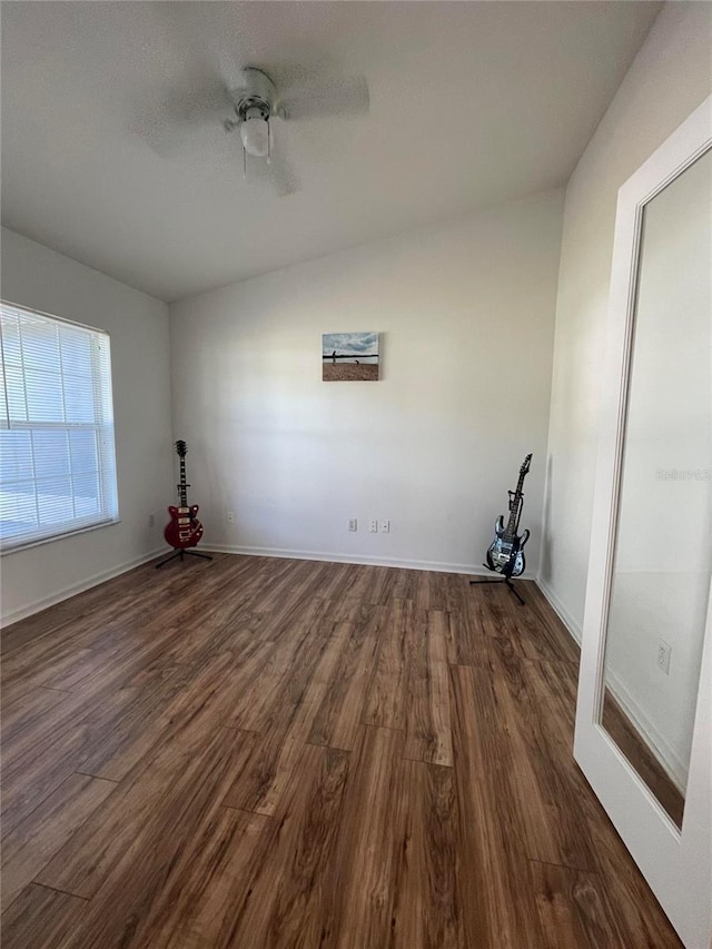 unfurnished room with dark wood-type flooring, a ceiling fan, and baseboards
