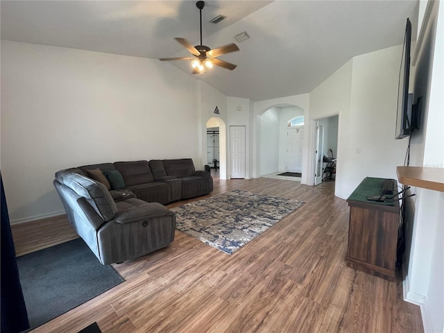 living area featuring arched walkways, a ceiling fan, wood finished floors, vaulted ceiling, and baseboards