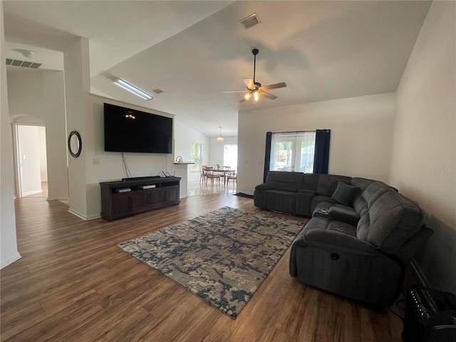 living area with arched walkways, a ceiling fan, wood finished floors, and baseboards