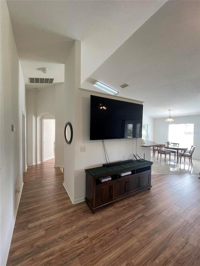 living area featuring wood finished floors, arched walkways, baseboards, and a textured ceiling