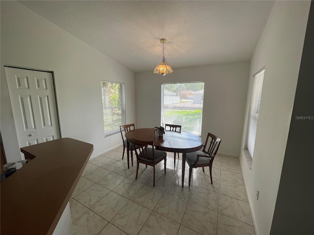 dining area featuring healthy amount of natural light, baseboards, vaulted ceiling, and light marble finish floors