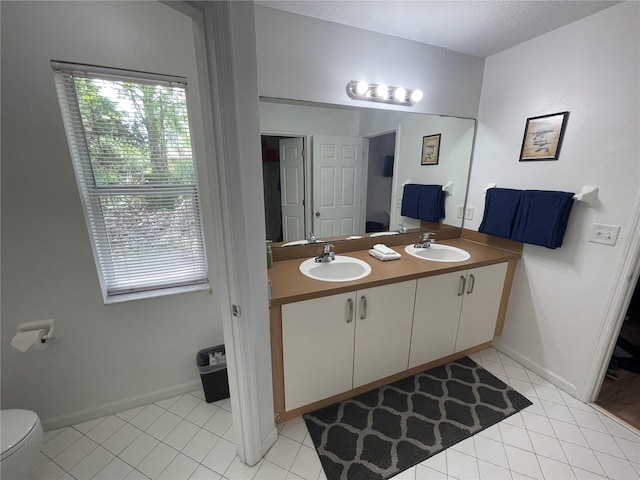 full bath with tile patterned flooring, healthy amount of natural light, double vanity, and toilet