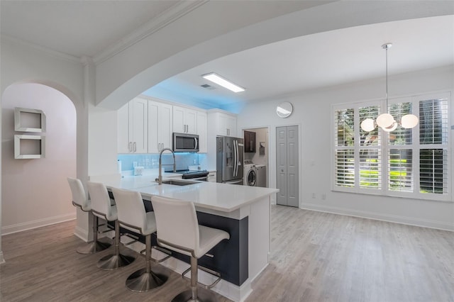 920 Cool Springs Cir, Ocoee, FL 34761 - kitchen with appliances with stainless steel finishes, a sink, light countertops, light wood-style floors, and arched walkways