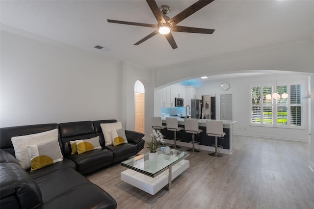 920 Cool Springs Cir, Ocoee, FL 34761 - living area featuring arched walkways, ceiling fan, light wood-style floors, ornamental molding, and a chandelier
