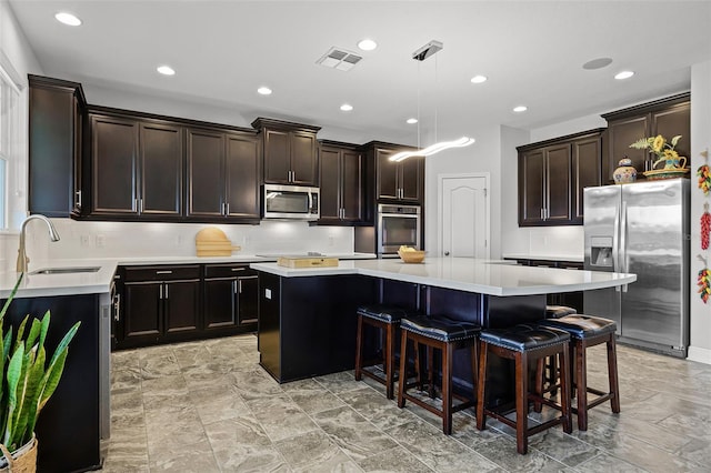 15208 Lake Claire Overlook Dr, Winter Garden, FL 34787 - kitchen featuring stainless steel appliances, a sink, a center island, a kitchen breakfast bar, and light countertops