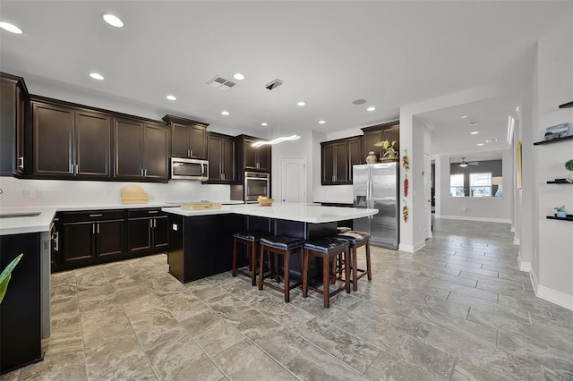 15208 Lake Claire Overlook Dr, Winter Garden, FL 34787 - kitchen featuring stainless steel appliances, a center island, light countertops, baseboards, and a kitchen bar