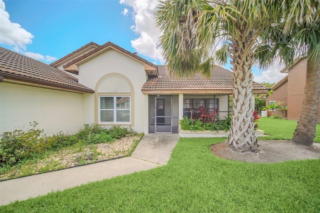 view of front of home featuring a front yard, stucco siding, and a tile roof