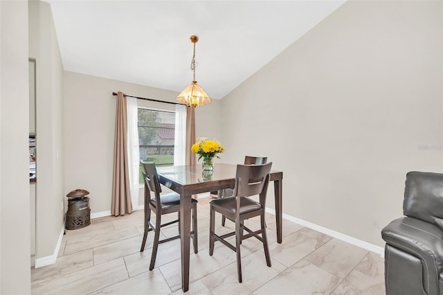 dining area with a chandelier, light marble finish flooring, baseboards, and vaulted ceiling