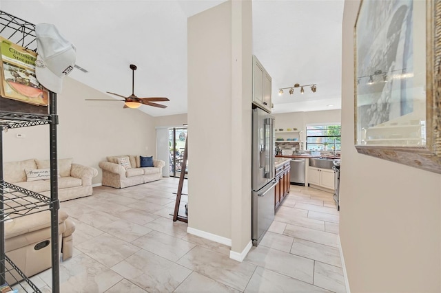 hall with light marble finish floors, rail lighting, lofted ceiling, and baseboards