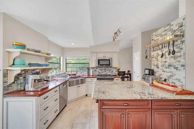 kitchen with stainless steel appliances, a sink, backsplash, light marble finish flooring, and light stone counters