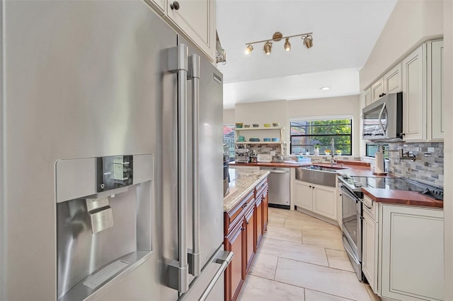 kitchen featuring stainless steel appliances, a sink, backsplash, and open shelves