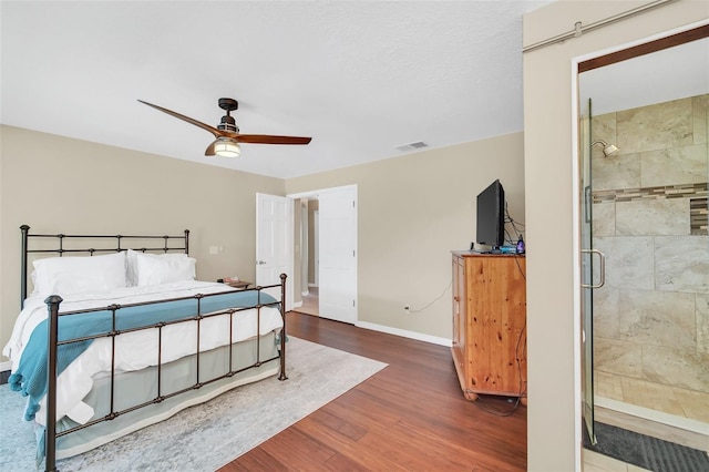 bedroom featuring wood finished floors, baseboards, ensuite bath, and a ceiling fan