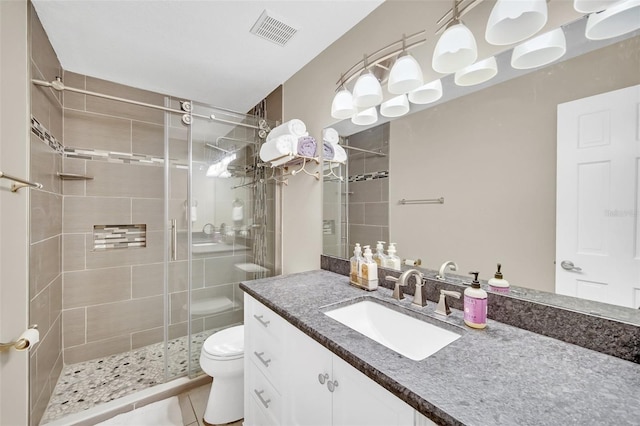 bathroom with a stall shower, toilet, vanity, and tile patterned floors