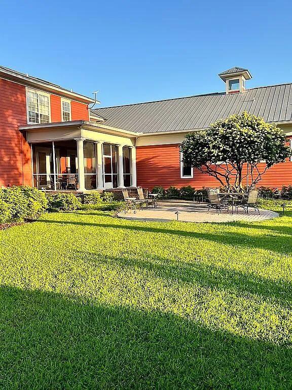 11317 NW 199th Ave, Alachua, FL 32615 - rear view of property featuring a lawn, a sunroom, and metal roof