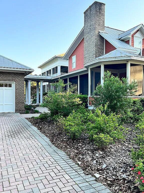 11317 NW 199th Ave, Alachua, FL 32615 - view of home's exterior featuring a standing seam roof, a chimney, metal roof, a sunroom, and an attached garage
