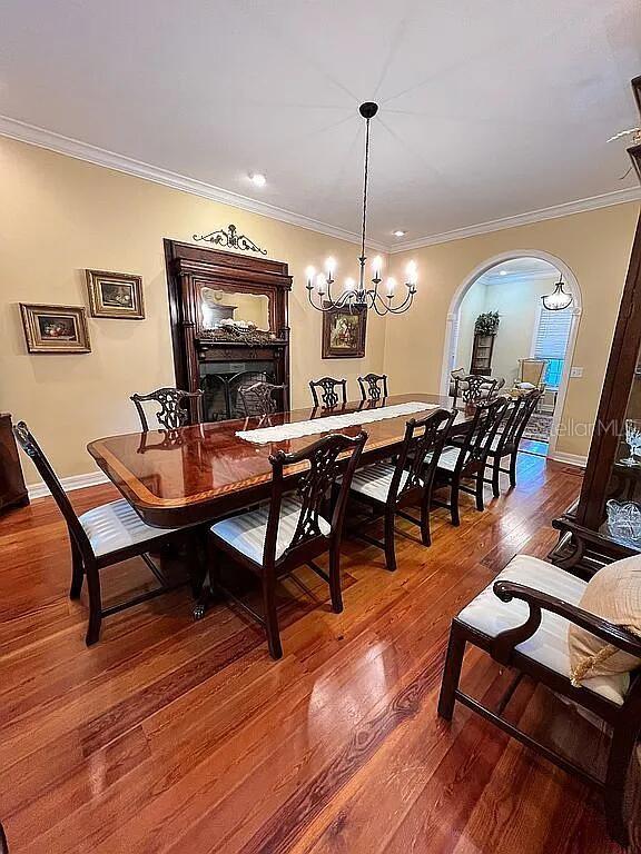 11317 NW 199th Ave, Alachua, FL 32615 - dining area with wood-type flooring, ornamental molding, a chandelier, baseboards, and arched walkways