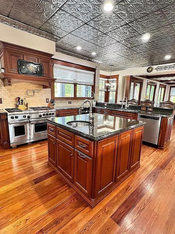 11317 NW 199th Ave, Alachua, FL 32615 - kitchen featuring appliances with stainless steel finishes, a sink, an ornate ceiling, wood finished floors, and a kitchen island with sink