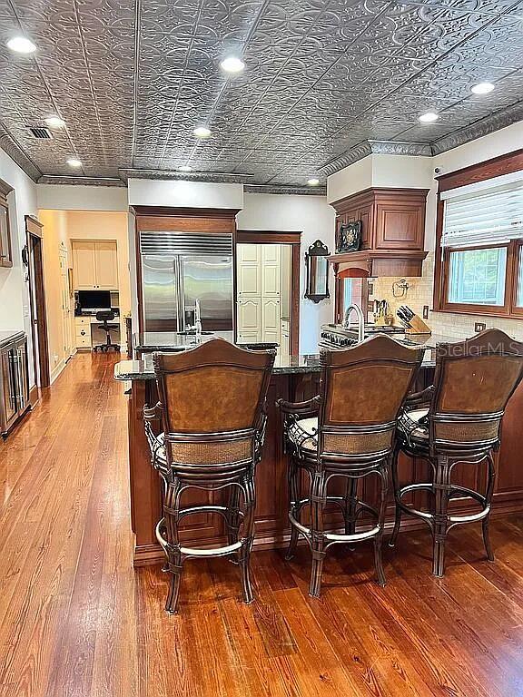 11317 NW 199th Ave, Alachua, FL 32615 - bar area featuring built in fridge, wood-type flooring, an ornate ceiling, and recessed lighting