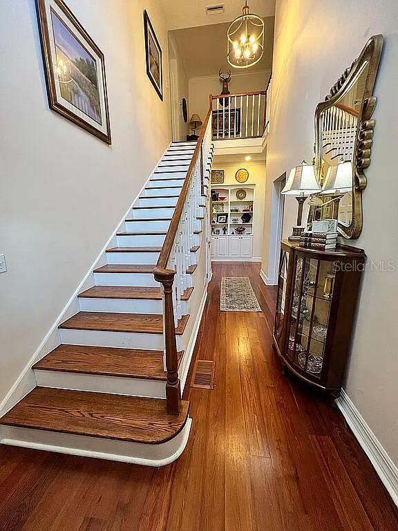 11317 NW 199th Ave, Alachua, FL 32615 - stairs featuring wood finished floors, a chandelier, baseboards, and a high ceiling