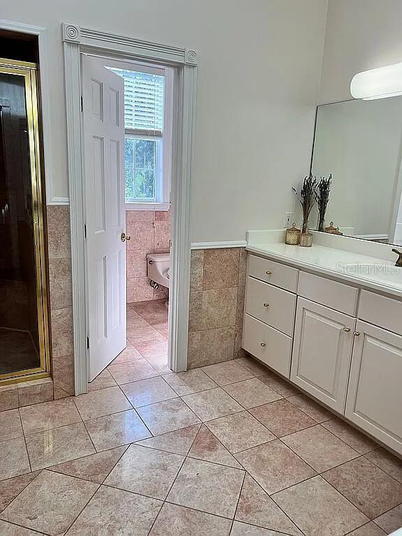 11317 NW 199th Ave, Alachua, FL 32615 - bathroom with tile walls, wainscoting, tile patterned flooring, a stall shower, and vanity