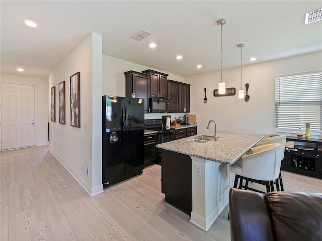 4553 Baler Trails Dr, Saint Cloud, FL 34772 - kitchen with black appliances, a sink, light wood-type flooring, an island with sink, and recessed lighting
