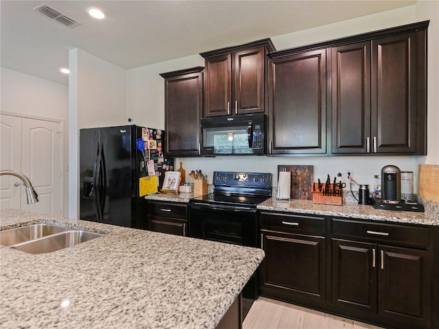 4553 Baler Trails Dr, Saint Cloud, FL 34772 - kitchen with black appliances, a sink, light stone counters, dark brown cabinetry, and recessed lighting