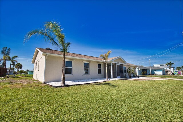 1933 Oregon Trl, Englewood, FL 34224 - back of house featuring stucco siding, a yard, and a sunroom