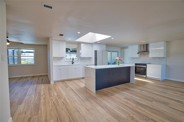 1933 Oregon Trl, Englewood, FL 34224 - kitchen with wall chimney exhaust hood, backsplash, a skylight, light wood-type flooring, and light countertops