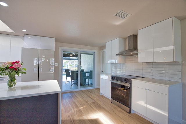 1933 Oregon Trl, Englewood, FL 34224 - kitchen featuring modern cabinets, wall chimney exhaust hood, electric range, light wood-style flooring, and recessed lighting