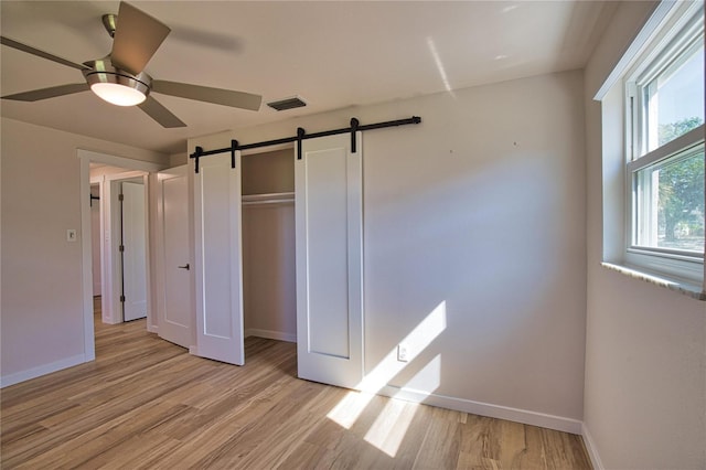 1933 Oregon Trl, Englewood, FL 34224 - unfurnished bedroom with a barn door, light wood finished floors, baseboards, and a closet
