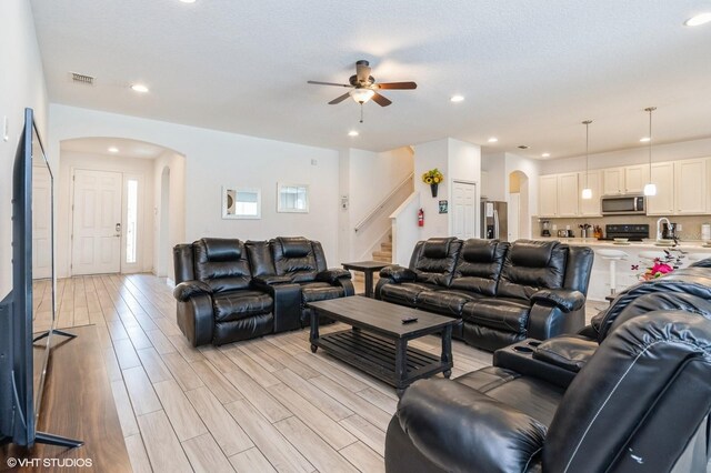 7017 Oakwood St, Davenport, FL 33837 - living area with arched walkways, a ceiling fan, stairway, light wood-style flooring, and recessed lighting