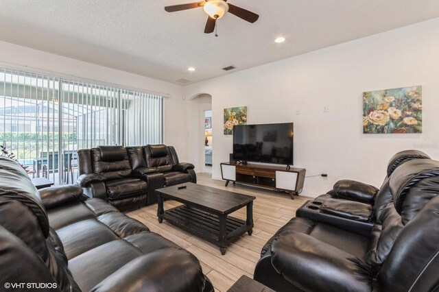 7017 Oakwood St, Davenport, FL 33837 - living room with light wood-style flooring, ceiling fan, arched walkways, and recessed lighting
