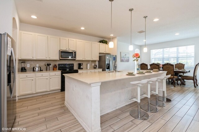 7017 Oakwood St, Davenport, FL 33837 - kitchen with appliances with stainless steel finishes, light wood-style flooring, tasteful backsplash, a sink, and light countertops