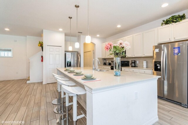 7017 Oakwood St, Davenport, FL 33837 - kitchen featuring stainless steel refrigerator with ice dispenser, a sink, light wood-style flooring, light countertops, and recessed lighting