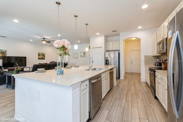 7017 Oakwood St, Davenport, FL 33837 - kitchen with appliances with stainless steel finishes, a sink, ceiling fan, arched walkways, and light wood finished floors