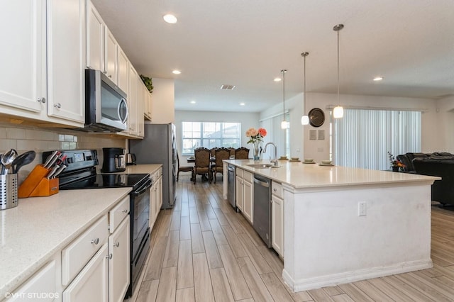 7017 Oakwood St, Davenport, FL 33837 - kitchen with stainless steel appliances, open floor plan, a sink, light wood-style floors, and recessed lighting