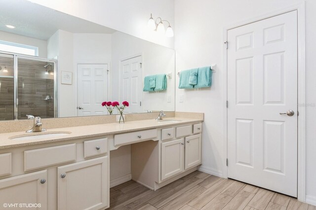 7017 Oakwood St, Davenport, FL 33837 - bathroom featuring double vanity, a shower stall, wood finished floors, and baseboards