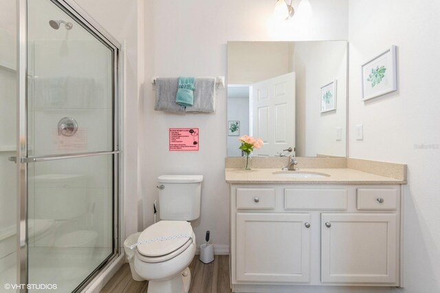7017 Oakwood St, Davenport, FL 33837 - bathroom with toilet, a stall shower, vanity, wood finished floors, and baseboards
