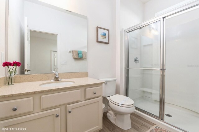 7017 Oakwood St, Davenport, FL 33837 - full bath with vanity, a shower stall, toilet, and wood finished floors