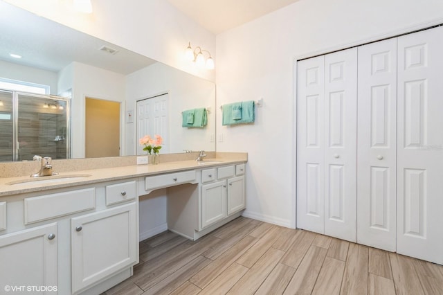 7017 Oakwood St, Davenport, FL 33837 - full bathroom with a closet, double vanity, a shower stall, wood finished floors, and baseboards