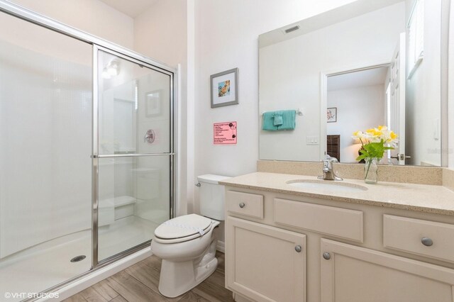 7017 Oakwood St, Davenport, FL 33837 - full bath featuring toilet, vanity, a shower stall, and wood finished floors