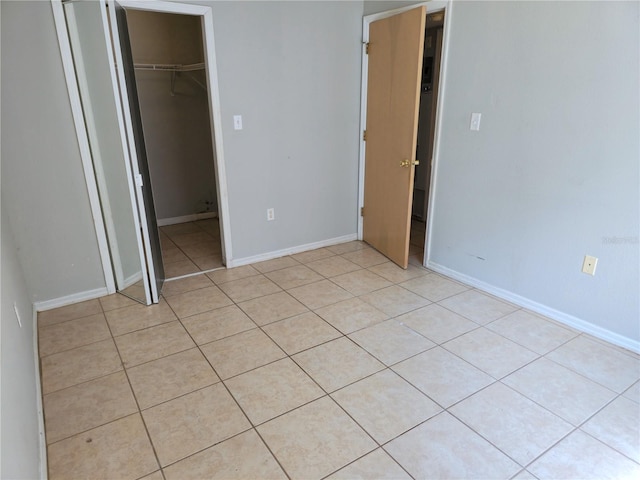 3157 Britannia Blvd Unit B, Kissimmee, FL 34747 - unfurnished bedroom featuring light tile patterned flooring, a walk in closet, a closet, and baseboards