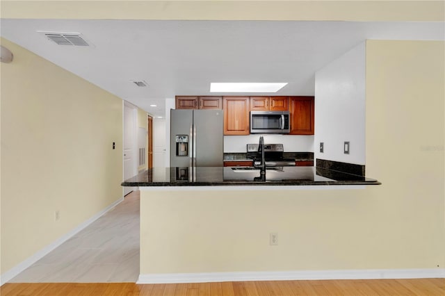 2020 Royal Bay Blvd Unit 91, Kissimmee, FL 34746 - kitchen with stainless steel appliances, a peninsula, dark stone countertops, brown cabinetry, and recessed lighting