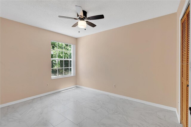 2020 Royal Bay Blvd Unit 91, Kissimmee, FL 34746 - unfurnished bedroom with a closet, a textured ceiling, baseboards, ceiling fan, and light marble finish floors
