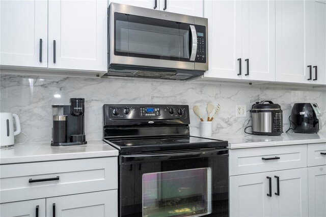 17614 Woodcrest Way, Clermont, FL 34714 - kitchen featuring stainless steel microwave, electric range, backsplash, white cabinets, and light countertops