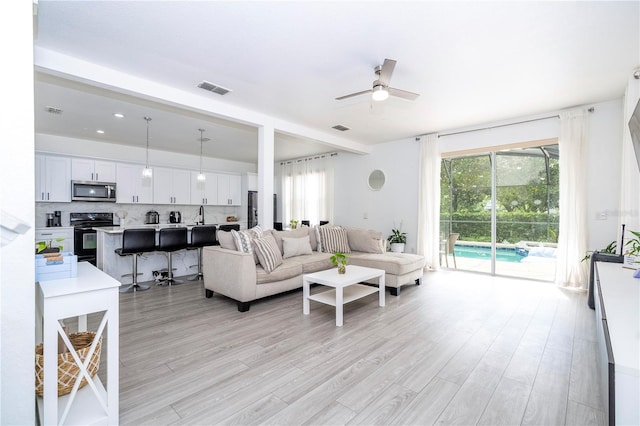17614 Woodcrest Way, Clermont, FL 34714 - living room with light wood-style floors, a ceiling fan, and healthy amount of natural light